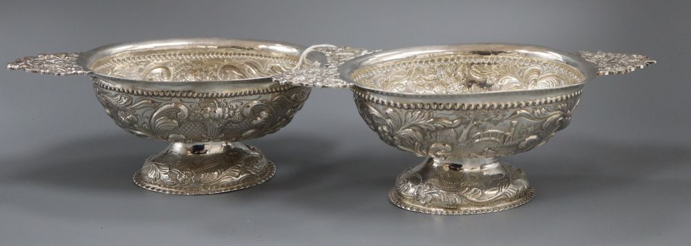 A matched pair of early 20th century Dutch repousse silver oval two handled pedestal sweetmeat dishes